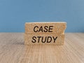 The words CASE STUDY is written on a brick blocks on a blue background. Wooden table.