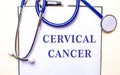 The words CERVICAL CANCER is written on a white sheet near the stethoscope. Medical concept