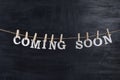 Words COMING SOON with clothespins on black background. Phrase from white letters Royalty Free Stock Photo