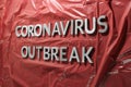 The words coronavirus outbreak laid with silver metal letters on crumpled red plastic film Royalty Free Stock Photo