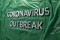 The words coronavirus outbreak laid with silver metal letters on green crumpled plastic film Royalty Free Stock Photo
