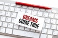 Words DREAMS COME TRUE written on torn paper on a computer keyboard Royalty Free Stock Photo