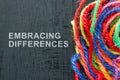 Words Embracing differences next to a ball of colored threads.