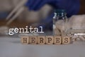 Words GENITAL HERPES composed of wooden dices. Pills, documents and a pen in the background