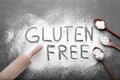 Words Gluten free written with flour and different kitchen utensils on grey background, flat lay Royalty Free Stock Photo