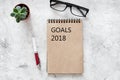 Words Goals for 2018 writting in notebook near glasses on grey stone background top view mockup