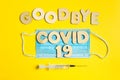 Words GOODBYE COVID 19 from wooden letters, syringe and facemask. Vaccination and the end of epidemic concept. Royalty Free Stock Photo