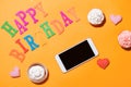 Words Happy Birthday with cupcake and smartphone on yellow background. Royalty Free Stock Photo