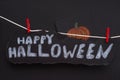 The words Happy Halloween on a black piece of paper hanging on a clothes line. Black Background