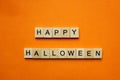 Words Happy Halloween. Wooden blocks with an inscription on an orange background. Bulletin board. The concept of the holiday is Royalty Free Stock Photo