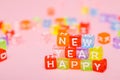 words happy new year made of colorful letters blocks on pink background. Flat lay, top view - holidays, winter, christmas and new Royalty Free Stock Photo