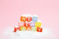 words happy new year made of colorful letters blocks on white snow and pink background. Flat lay, top view - holidays, winter, chr Royalty Free Stock Photo