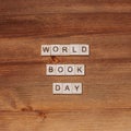 Words happy world book day made of wooden blocks with stack of books. Background for book holiday on wooden table top