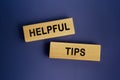 The words Helpful tips is written on a wooden blocks on a dark blue background. Concept text Royalty Free Stock Photo