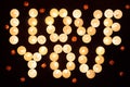 Words I LOVE YOU formed by glowing candles and decorated with flowers.