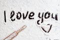 Words I love you hand-painted on a dark table covered with white flour, wooden rolling pin lies diagonally, cooking for Royalty Free Stock Photo