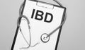 The words ibd is written on white paper on a grey background near a stethoscope. Medical concept