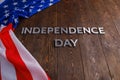 the words independence day laid on brown wooden planks surface with crumpled unated states of america flag