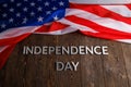 the words independence day laid on brown wooden planks surface with crumpled unated states of america flag