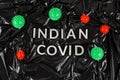 words indian covid laid with silver metal letters on crumpled black plastic bag background with small virus models Royalty Free Stock Photo