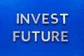 The words invest future laid with silver metal characters on blue painted wooden board in central flat lay composition Royalty Free Stock Photo