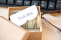 Words IRA 401k ROTH print on white pieces of paper, money dollars and glasses on table Royalty Free Stock Photo