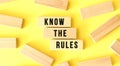 The words KNOW THE RULES are written on scattered wooden blocks on a yellow background.