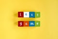 Words Last Game made from colored wooden blocks. They are arranged in two rows. Painted cubes with letters on yellow background. Royalty Free Stock Photo
