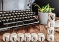 Words LATEST NEWS on wooden blocks with vintage typewriter and potted plant in background