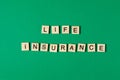 Words life insurance by wooden blocks on green background. Royalty Free Stock Photo