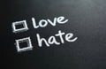 Words love and hate written with chalk on dark board with empty checkboxes. Symbol of making a choice between positive and Royalty Free Stock Photo