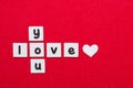 Words Love Yon written by black printed letters on white sheets of paper in crossword with little white heart on red background