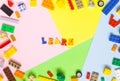 Words made of multi-colored wooden letters `learn` on a multi-colored background, children`s construction kit around.