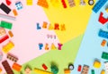 Words made of multi-colored wooden letters `learn and play` on a multi-colored background, children`s construction kit around.