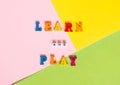 Words made of multi-colored wooden letters `learn and play` on a multi-colored background