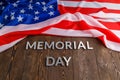 the words memorial day laid with silver metal letters on wooden board surface with crumpled usa flag above