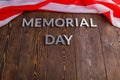 the words memorial day laid with silver metal letters on wooden board surface with crumpled usa flag below