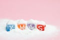 words merry christmas made of colorful letters blocks on white snow and pink background. Flat lay, top view - holidays, winter, ch Royalty Free Stock Photo