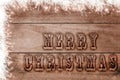 Words Merry Christmas written, burned letters on wooden snowy brown background Royalty Free Stock Photo