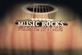 Words Music Rocks with wooden letters, on reflecting surface of an acoustic guitar. Guitars bridge perspective. Creative grungy Royalty Free Stock Photo