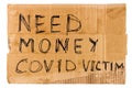 Words need money covid victim handwritten on rectangular flat sheet of cardboard - homeless placard, isolated on white