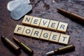 The words never forget with bullets and old and worn military dog tags on rusty metal background.