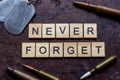 The words never forget with bullets and old and worn military dog tags on rusty metal background.