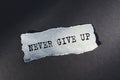 Words NEVER GIVE UP appearing on torn gray paper. Business and motivational concept. Copy space Royalty Free Stock Photo