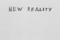 the words new reality handwritten on blank white paper with pencil