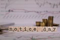 Words NOTICE DAY composed of wooden letter. Stacks of coins in the background Royalty Free Stock Photo