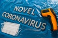 Words novel coronavirus laid with metal letters on crumpled blue plastic film backdrop with face masks and thermometer