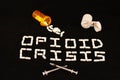 Opioid crisis spelled out with white pills on a black background with spilled prescription pills and a pill cutter. Royalty Free Stock Photo