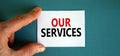 Words `our services` on the white card between fingers. Beautiful blue background, business concept. Copy space