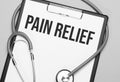 The words Pain Relief is written on white paper on a grey background near a stethoscope. Medical concept Royalty Free Stock Photo